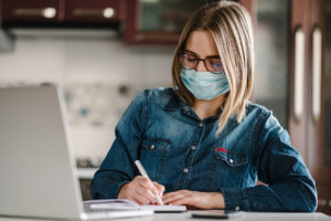 Woman working at her computer wearing a coronavirus prevention mask